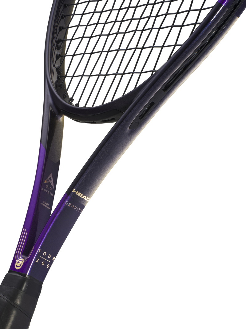 Close-up studio shot of a tennis racket showing the black and purple frame, black strings, and part of the grip against a white background. Visible branding includes HEAD logo.